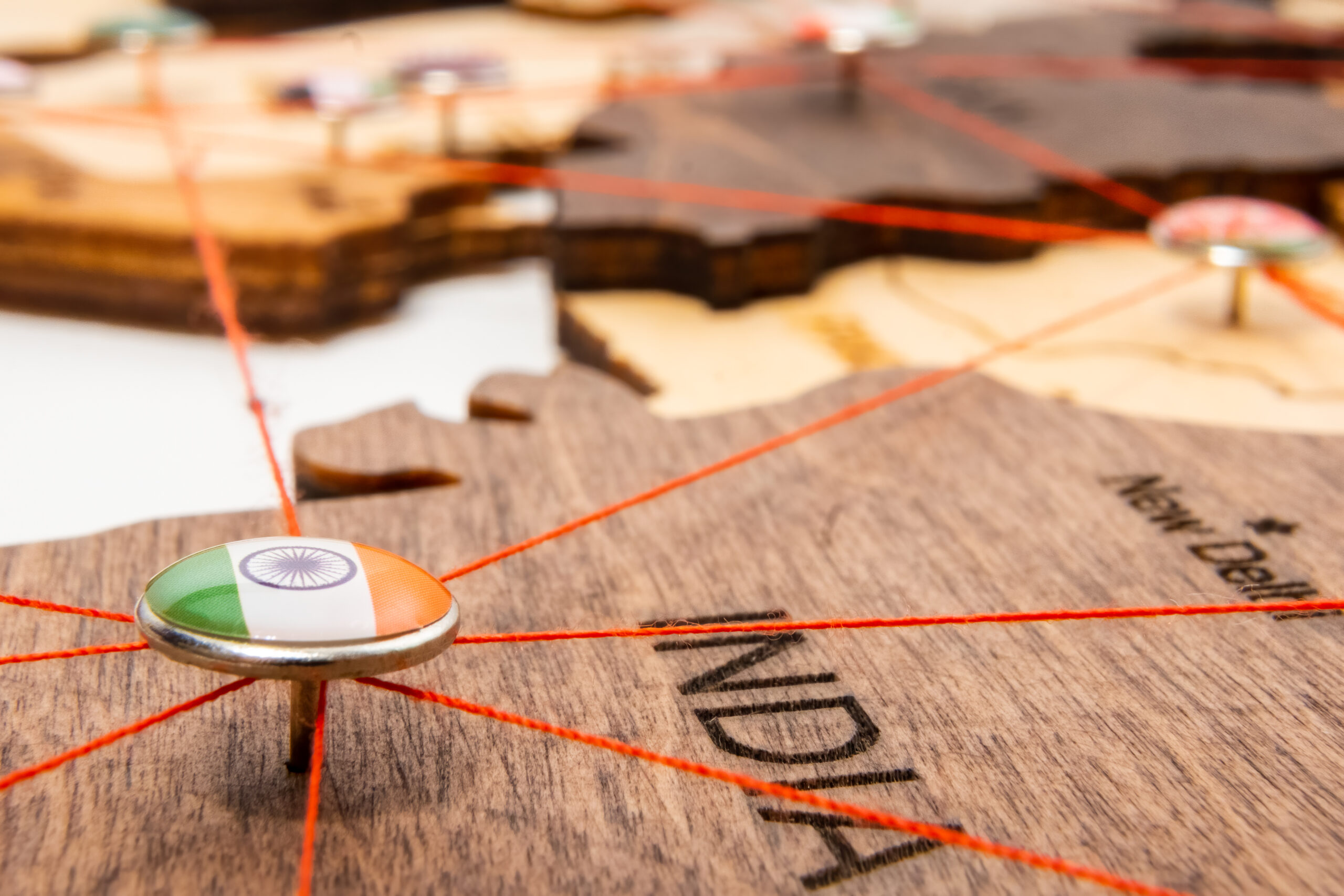 India flag on the pushpin and red thread on the wooden map, close up