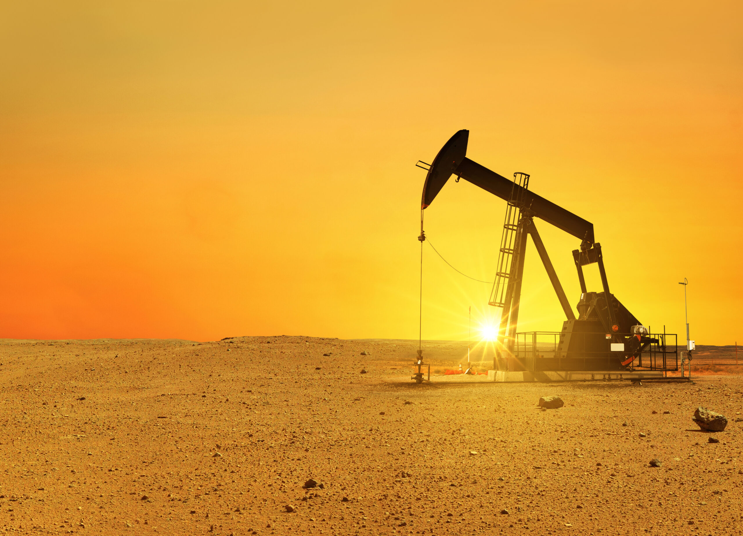 Pumpjack rig pumps oil in the desert at sunset. Dead land and sa